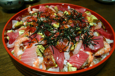 Chirashizushi med rå fisk och sjögräs på en risbädd